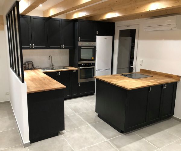 Cuisine tendance rénovée avec meubles noirs, bois massif et verrière