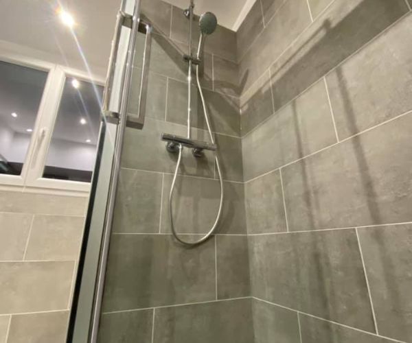 Douche moderne avec carrelage gris et robinetterie chrome