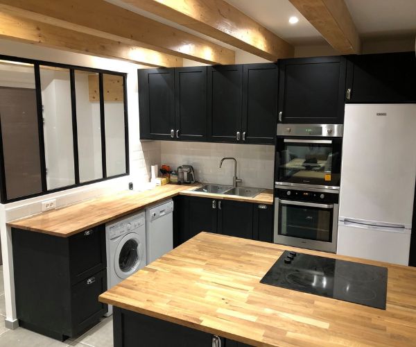 Plan de travail en bois et meubles noirs dans une cuisine rénovée moderne