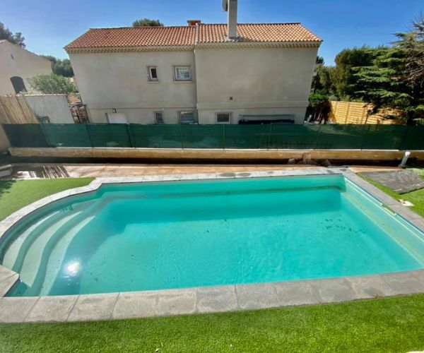 Vue plongeante sur la piscine rénovée avec margelles en travertin à Carry-le-Rouet