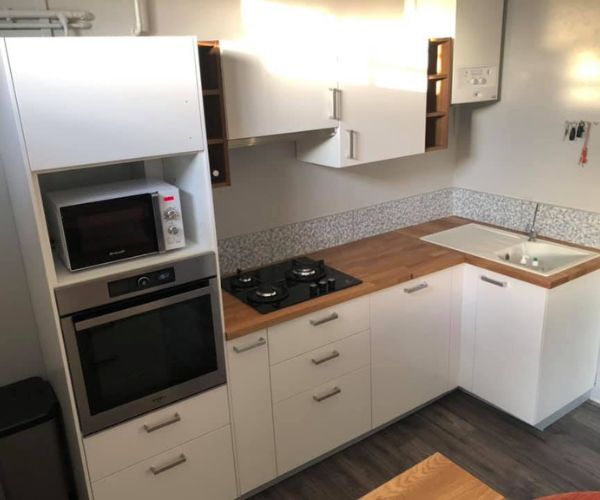 Cuisine rénovée avec meubles blancs, plan de travail bois et électroménager intégré