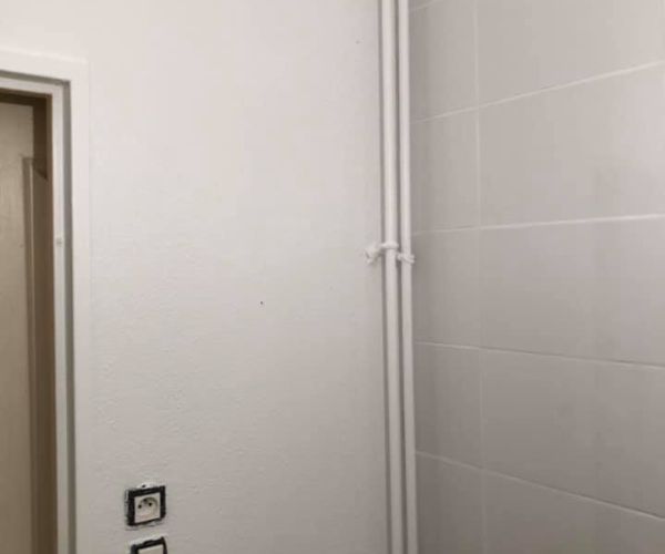 Salle de bain avant rénovation avec murs abîmés et plomberie apparente