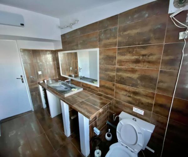 Salle de bain avant rénovation avec carrelage foncé et meuble à rénover