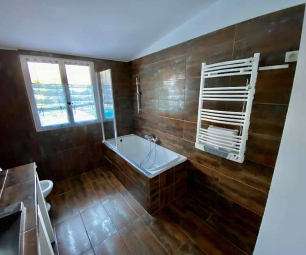 Salle de bain avant rénovation avec baignoire et carrelage foncé