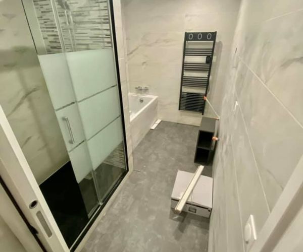 Salle de bain rénovée avec sol PVC effet béton et carrelage moderne