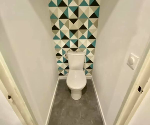 WC rénovés avec sol PVC effet béton et mur décoratif géométrique